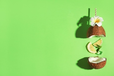 Photo of Creative image of summer cocktail made with coconut, lemon slice, mint, ice and straw on green background, top view. Space for text