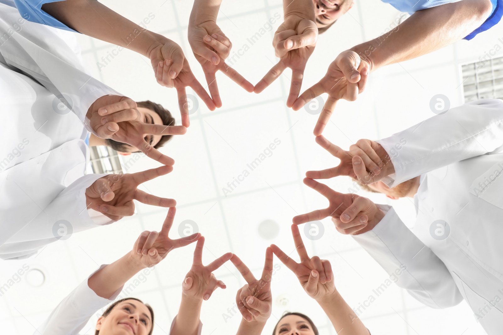 Photo of Team of medical workers holding hands together in hospital, bottom view. Unity concept