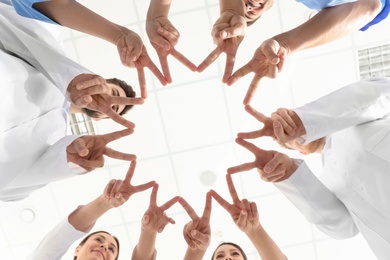 Team of medical workers holding hands together in hospital, bottom view. Unity concept