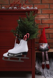 Pair of ice skates with Christmas decor hanging on red wooden cabinet indoors