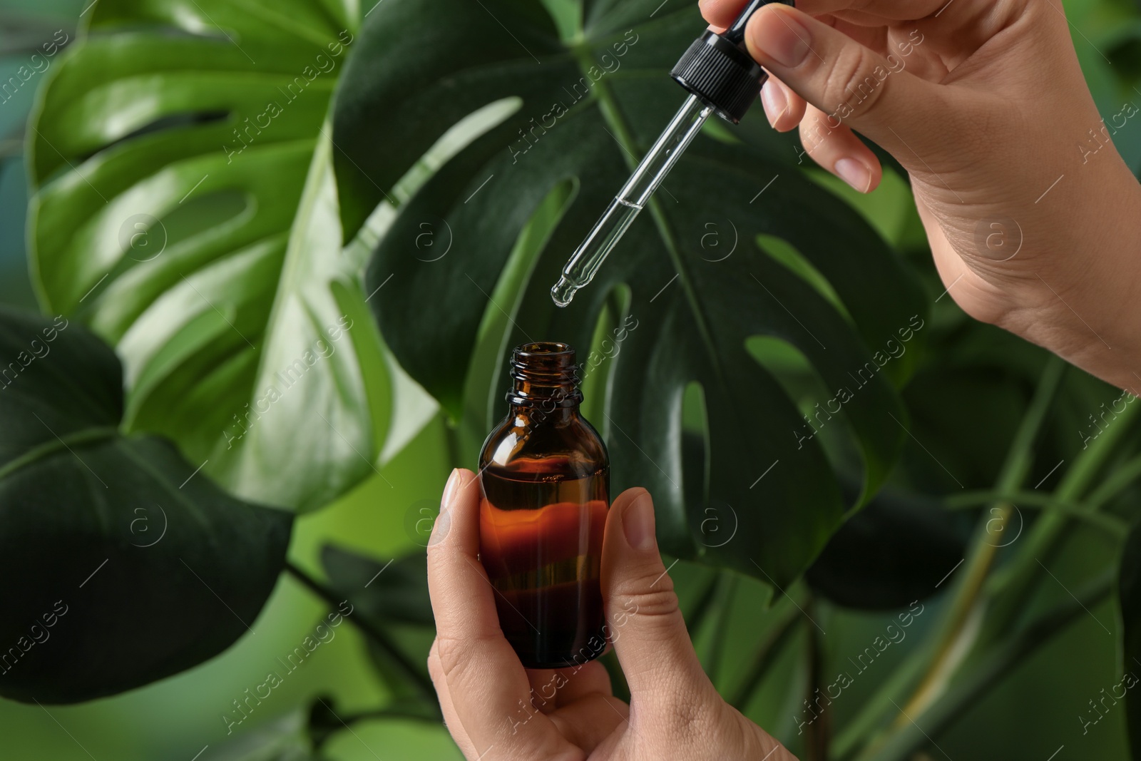 Photo of Woman with bottle of cosmetic serum and pipette on green background, closeup