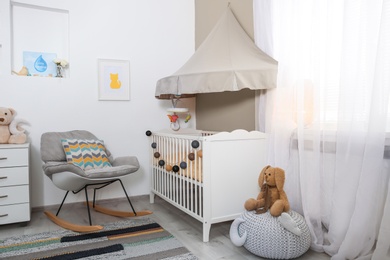 Photo of Cozy baby room interior with crib and rocking chair