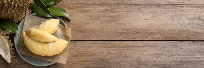 Image of Fresh ripe durians and leaves on wooden table, flat lay with space for text. Banner design