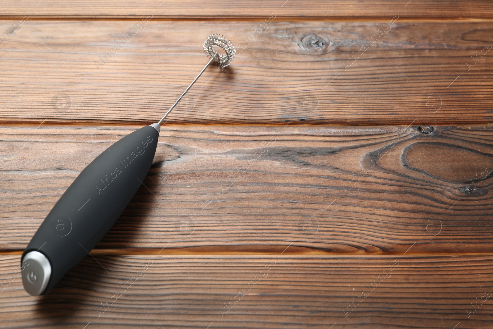 Photo of Black milk frother wand on wooden table, space for text