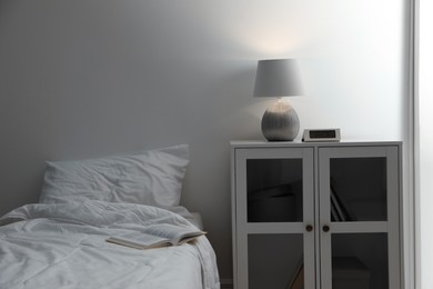 Stylish lamp and alarm clock on bedside table indoors. Bedroom interior elements