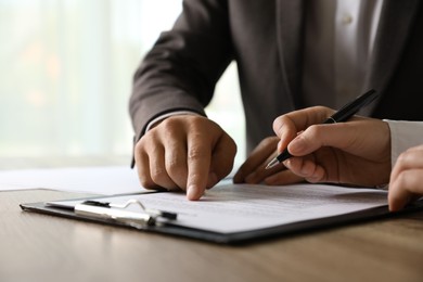 Photo of Businesspeople working with document at table indoors, closeup