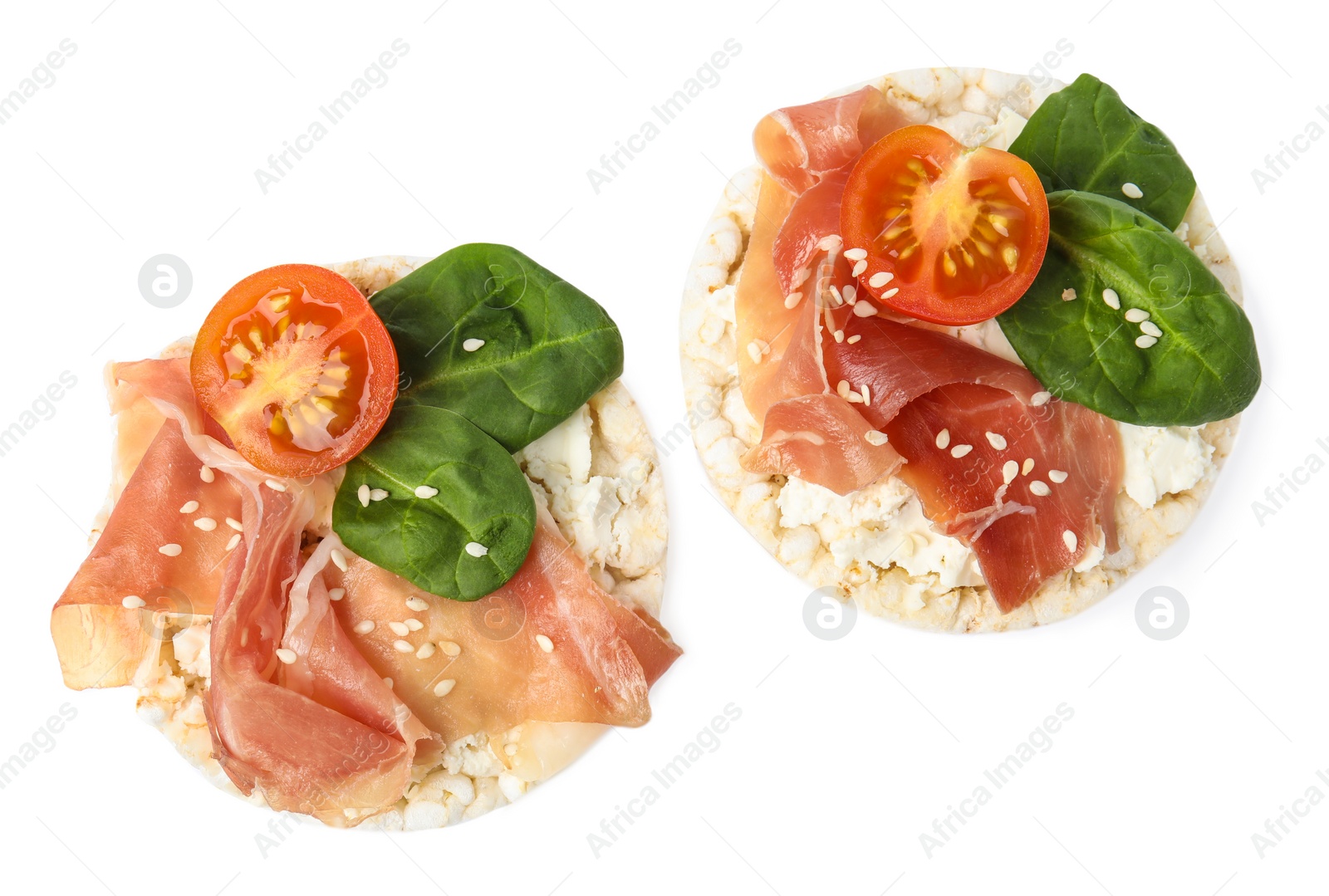 Photo of Puffed rice cakes with prosciutto, tomato and basil isolated on white, top view