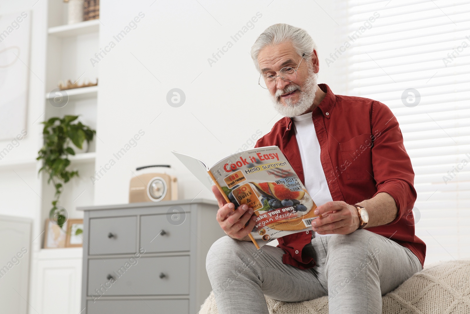 Photo of Senior man in eyeglasses reading magazine on bed at home, space for text