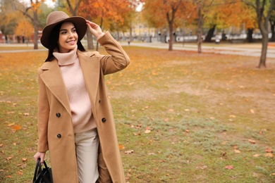 Photo of Young woman wearing stylish clothes in autumn park, space for text
