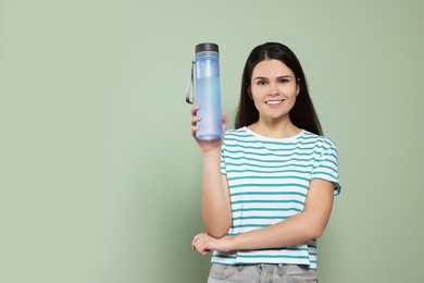 Young woman with bottle of water on green background. Space for text