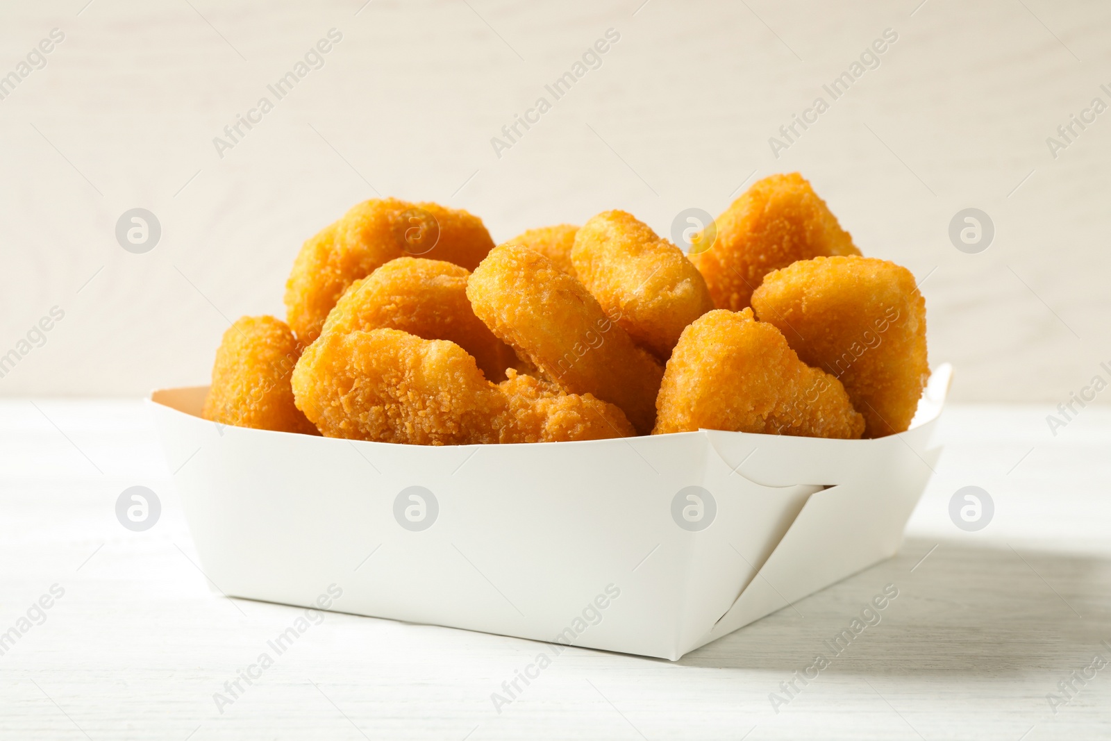 Photo of Tasty fried chicken nuggets on white wooden table