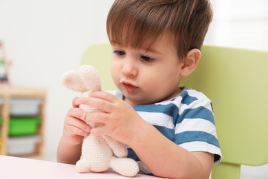 Little child playing with stuffed bunny at table