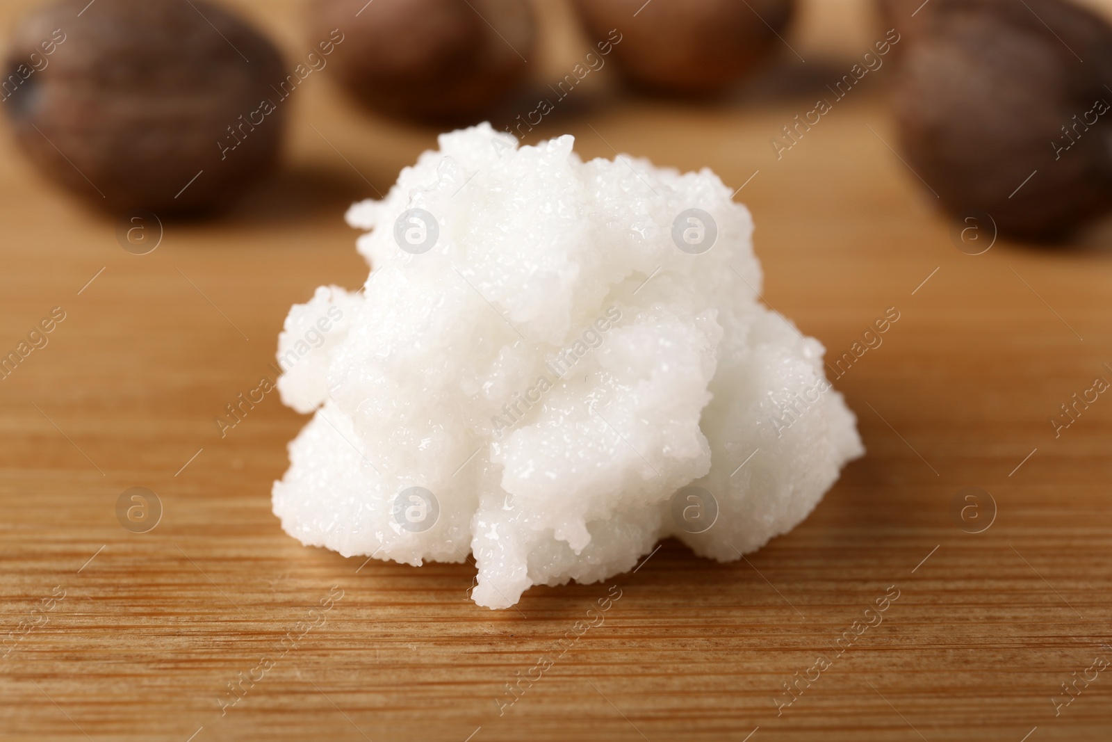 Photo of Fresh shea butter on wooden table, closeup. Cosmetic product