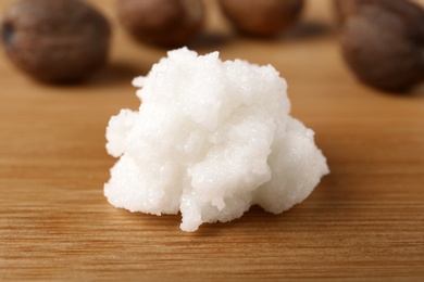 Photo of Fresh shea butter on wooden table, closeup. Cosmetic product