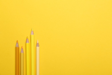 Photo of Color pencils on yellow background, flat lay. Space for text