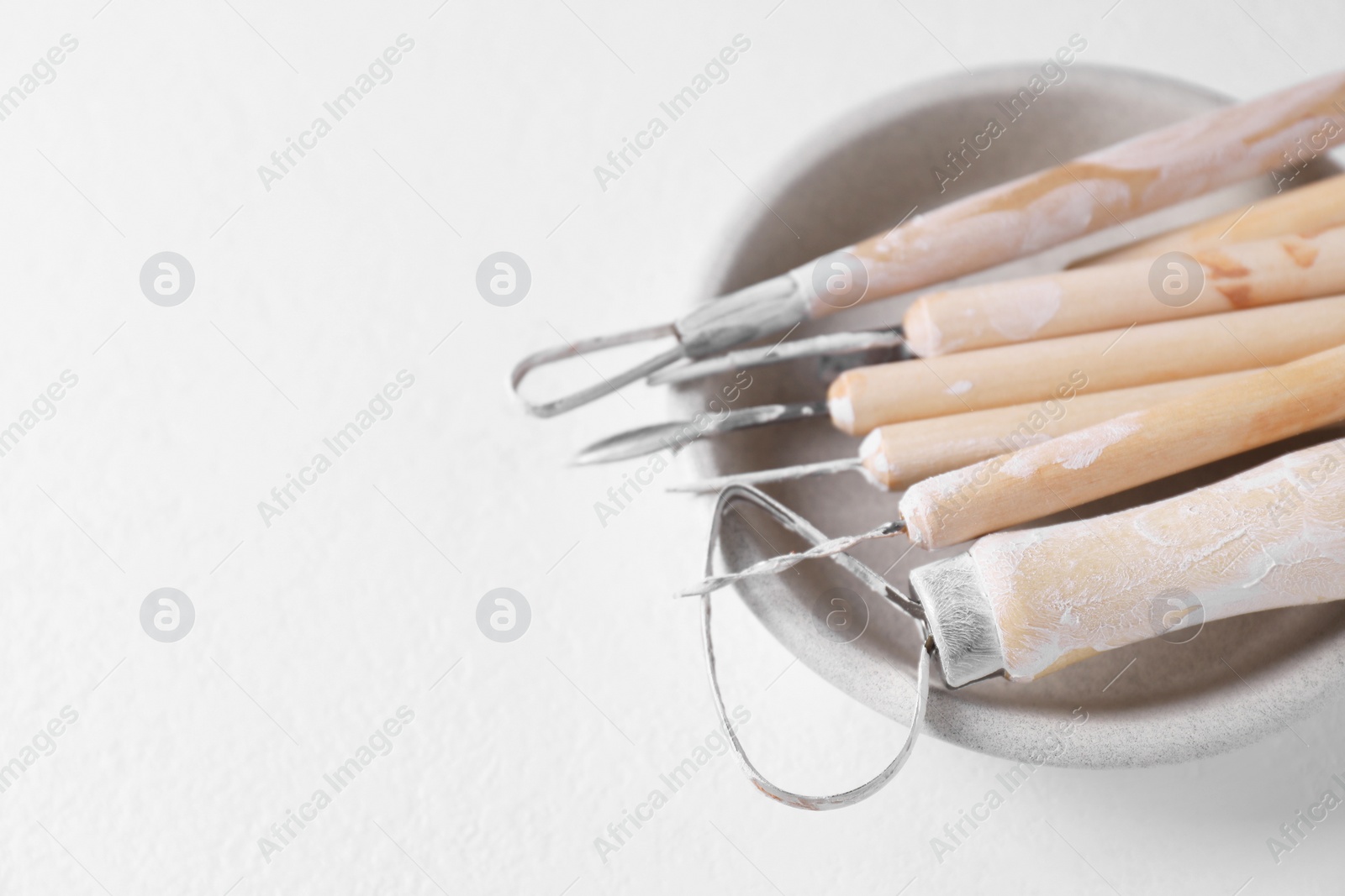 Photo of Set of different clay crafting tools on white table, closeup. Space for text