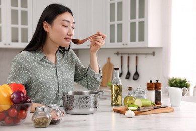 Photo of Beautiful woman tasting food after cooking in kitchen
