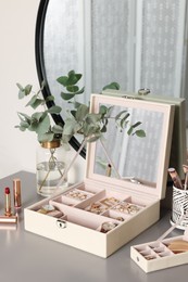 Photo of Elegant jewelry boxes with expensive wristwatches and beautiful bijouterie on grey table in room