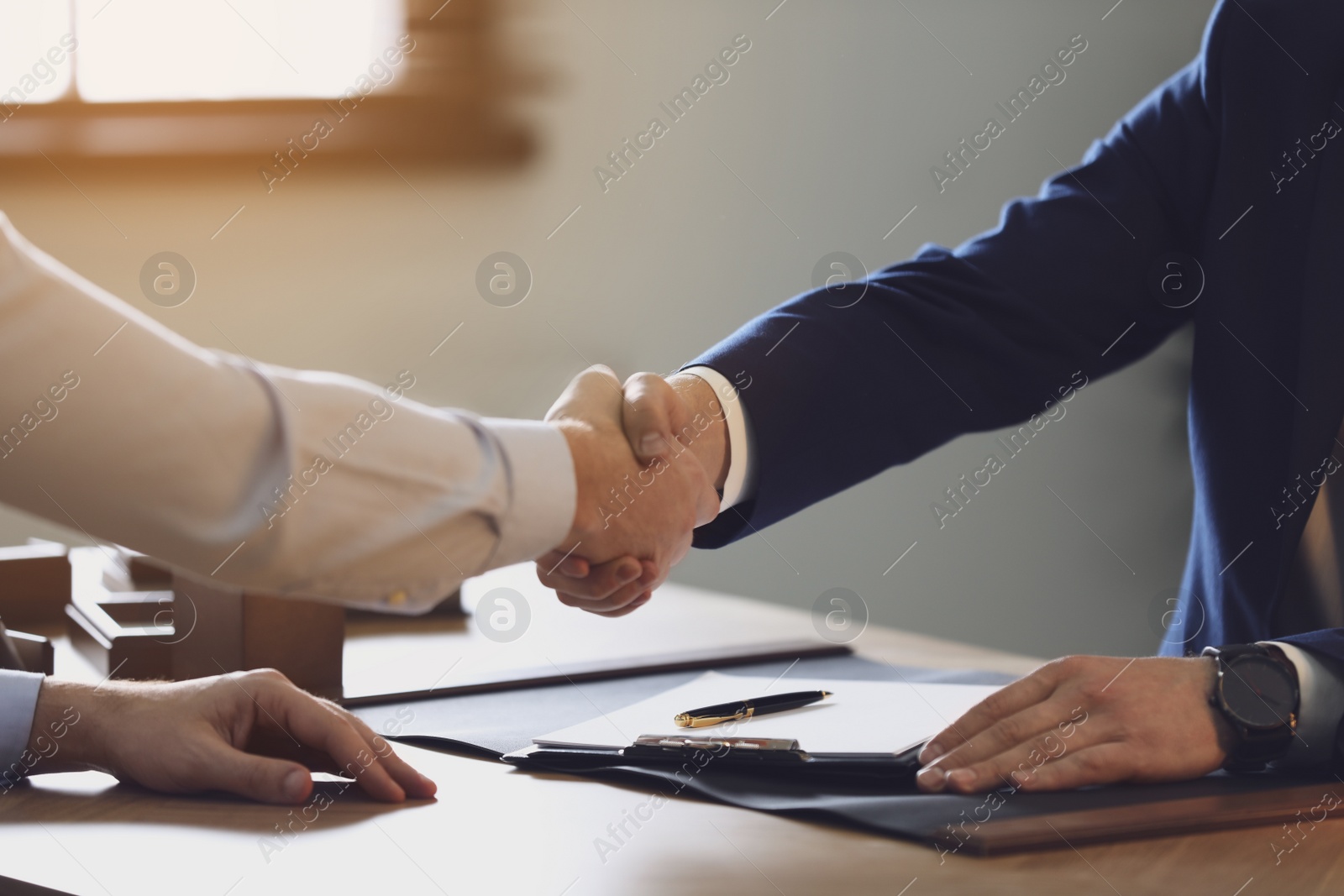 Photo of Male lawyer shaking hands with client in office, closeup