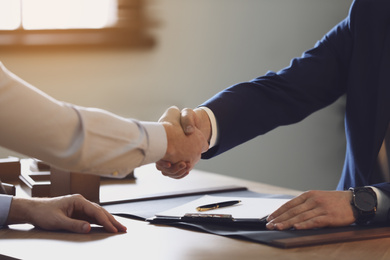 Male lawyer shaking hands with client in office, closeup