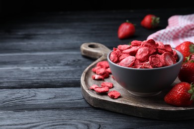 Photo of Freeze dried and fresh strawberries on black wooden table. Space for text