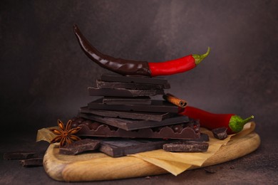 Red hot chili peppers and pieces of dark chocolate with spices on grey table