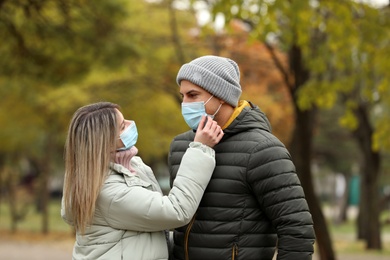 Photo of Couple in medical masks outdoors on autumn day. Protective measures during coronavirus quarantine