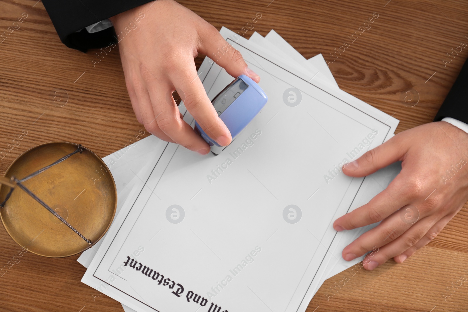 Photo of Male notary stamping document at wooden table, top view