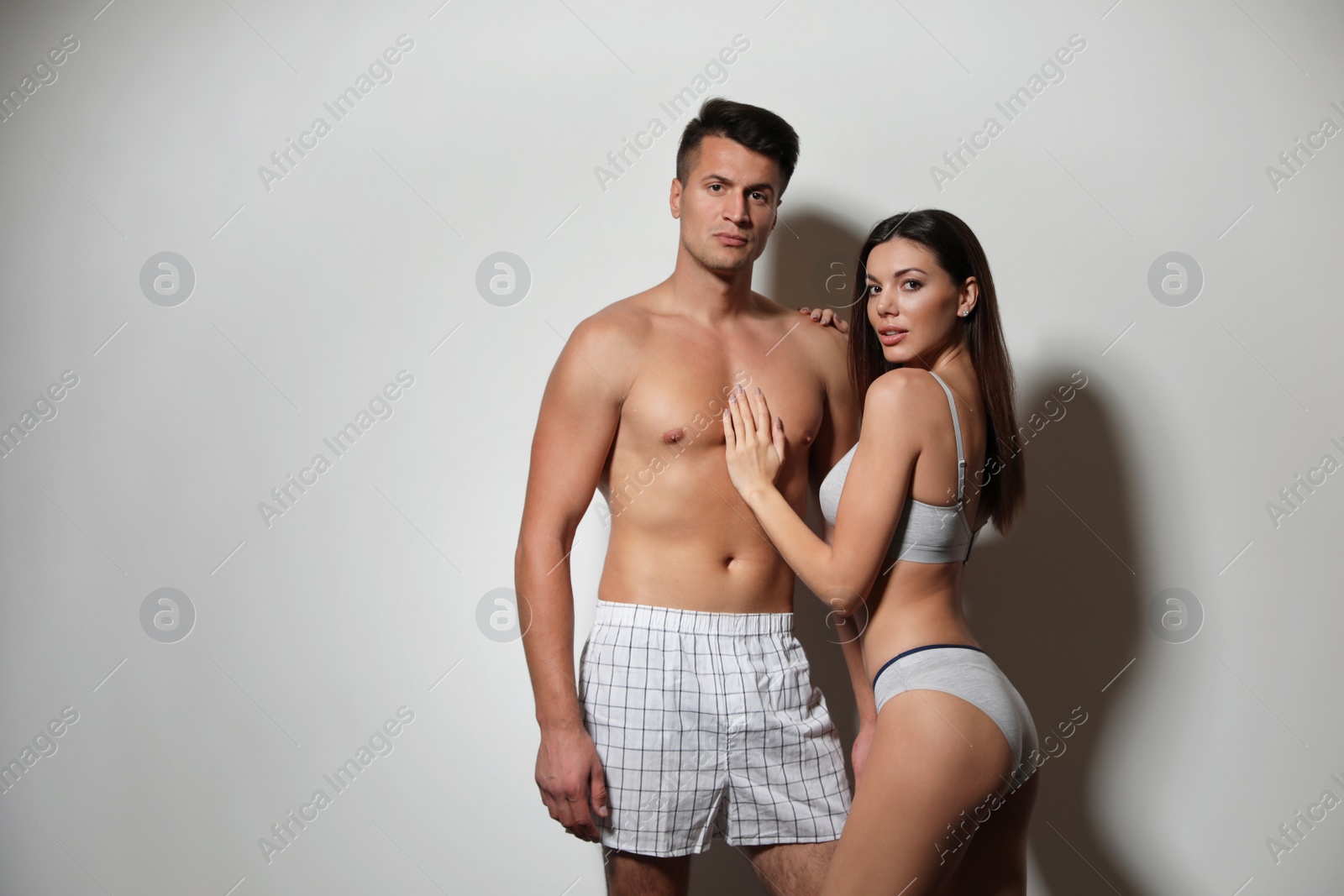Photo of Young couple wearing underwear on light grey background, space for text