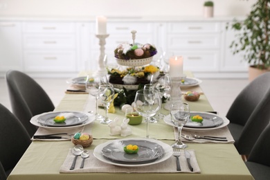 Beautiful Easter table setting with burning candles indoors