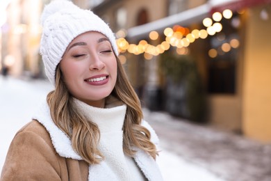 Photo of Portrait of smiling woman on city street in winter. Space for text