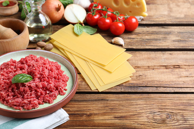 Fresh ingredients for lasagna on wooden table