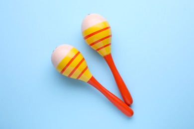 Photo of Colorful maracas on light blue background, flat lay. Musical instrument