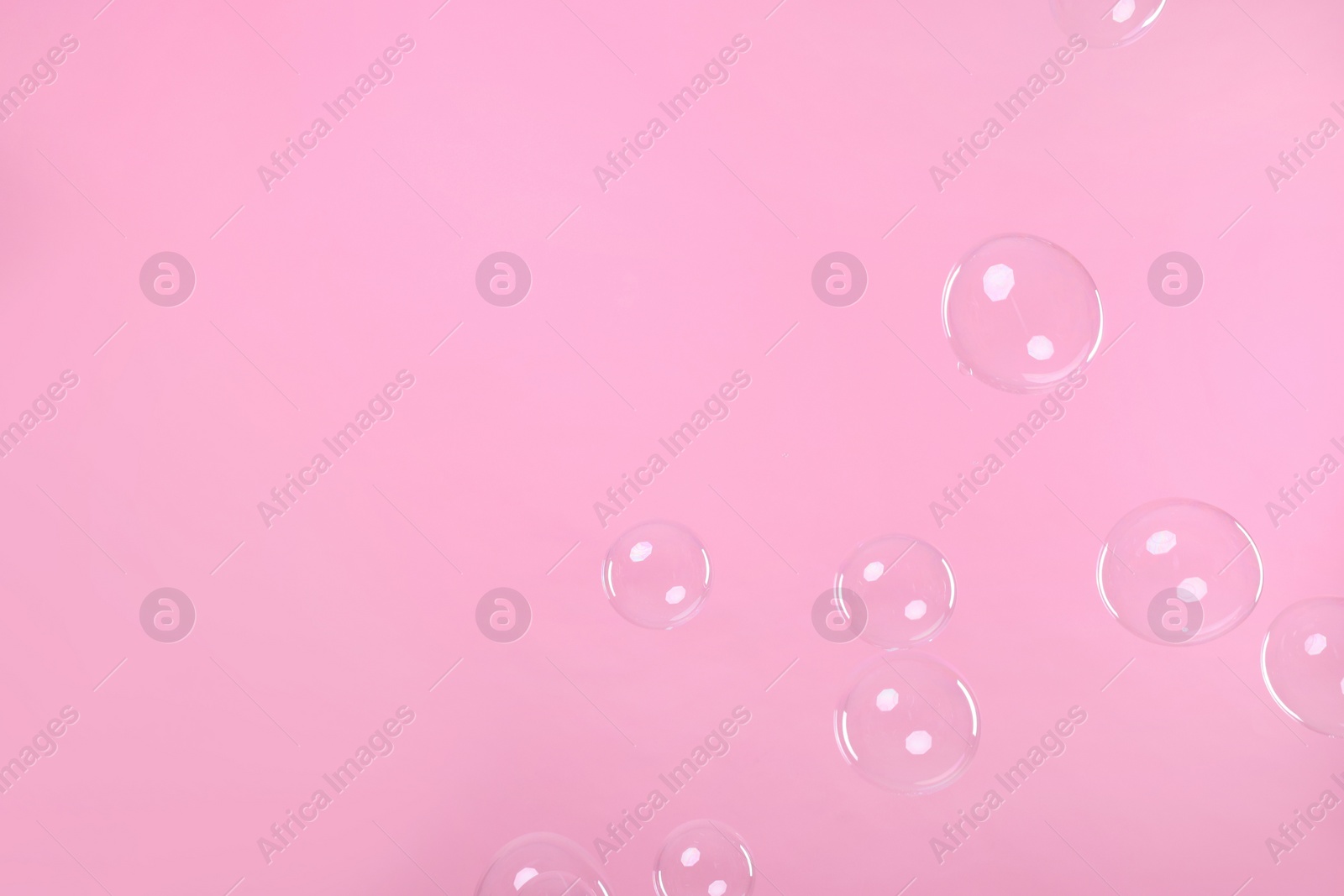 Photo of Many beautiful soap bubbles on pink background. Space for text
