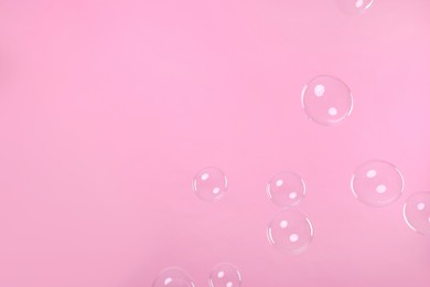 Photo of Many beautiful soap bubbles on pink background. Space for text