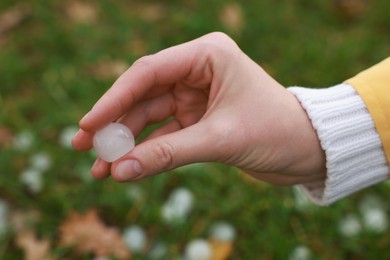 Woman holding hail grain after thunderstorm outdoors, closeup