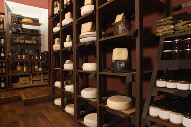 Different types of delicious cheeses on rack in store