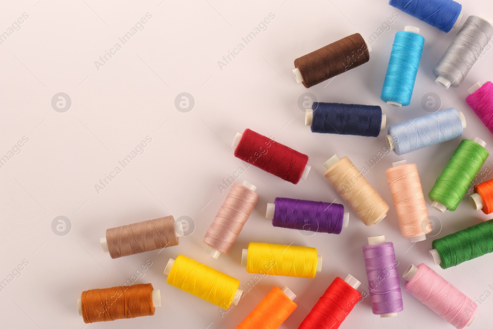 Photo of Set of colorful sewing threads on white background, top view