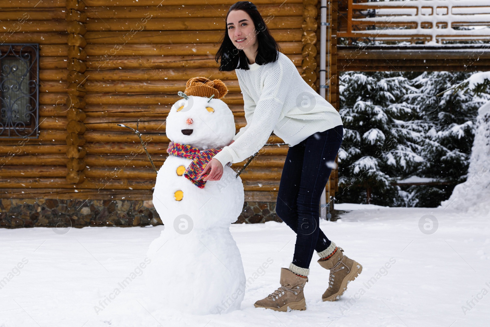 Photo of Young woman near funny snowman outdoors. Winter vacation