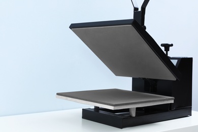 Heat press machine on table against light background