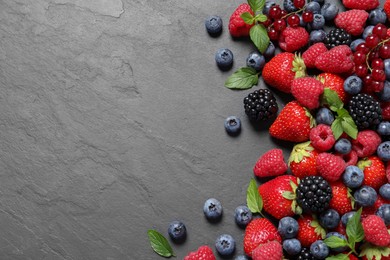 Photo of Many different fresh ripe berries on dark grey table, flat lay. Space for text