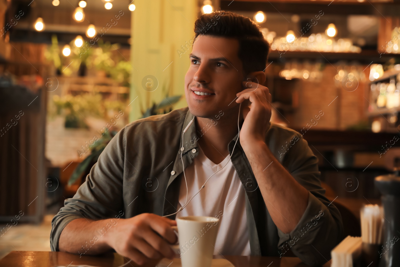 Photo of Man listening to audiobook at table in cafe