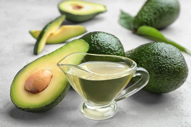 Photo of Composition with natural oil and avocados on grey stone background