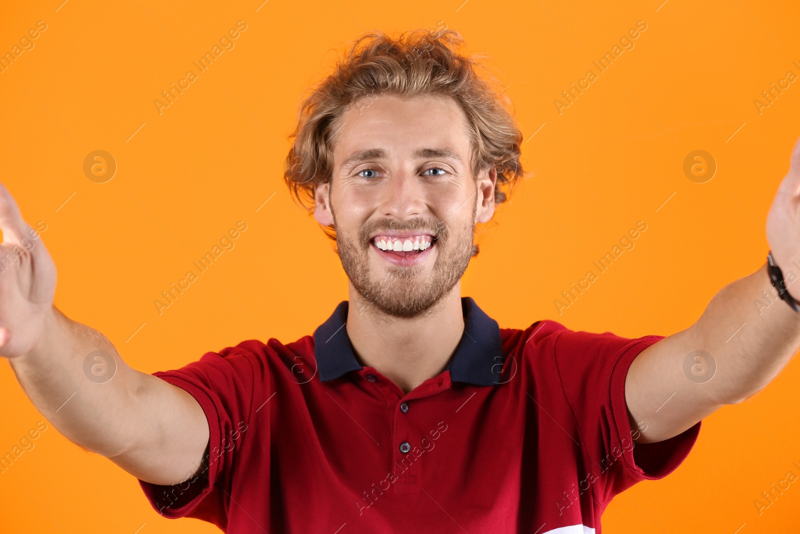 Photo of Handsome young man laughing and taking selfie on color background