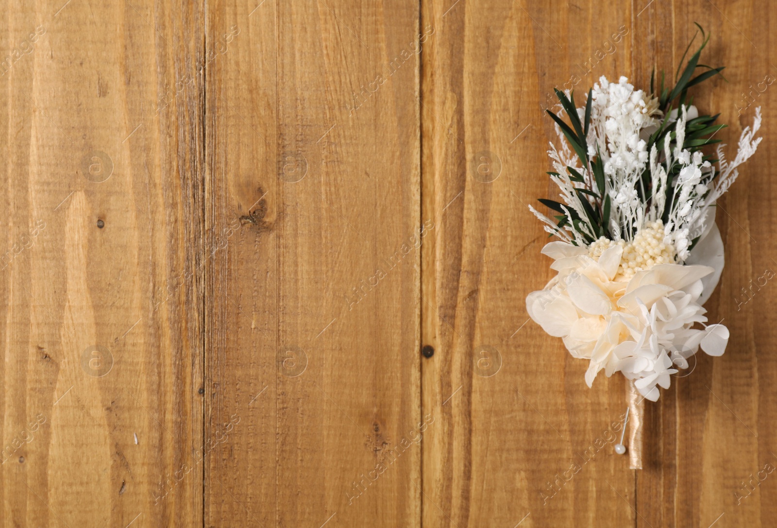 Photo of Stylish boutonniere on wooden table, top view. Space for text