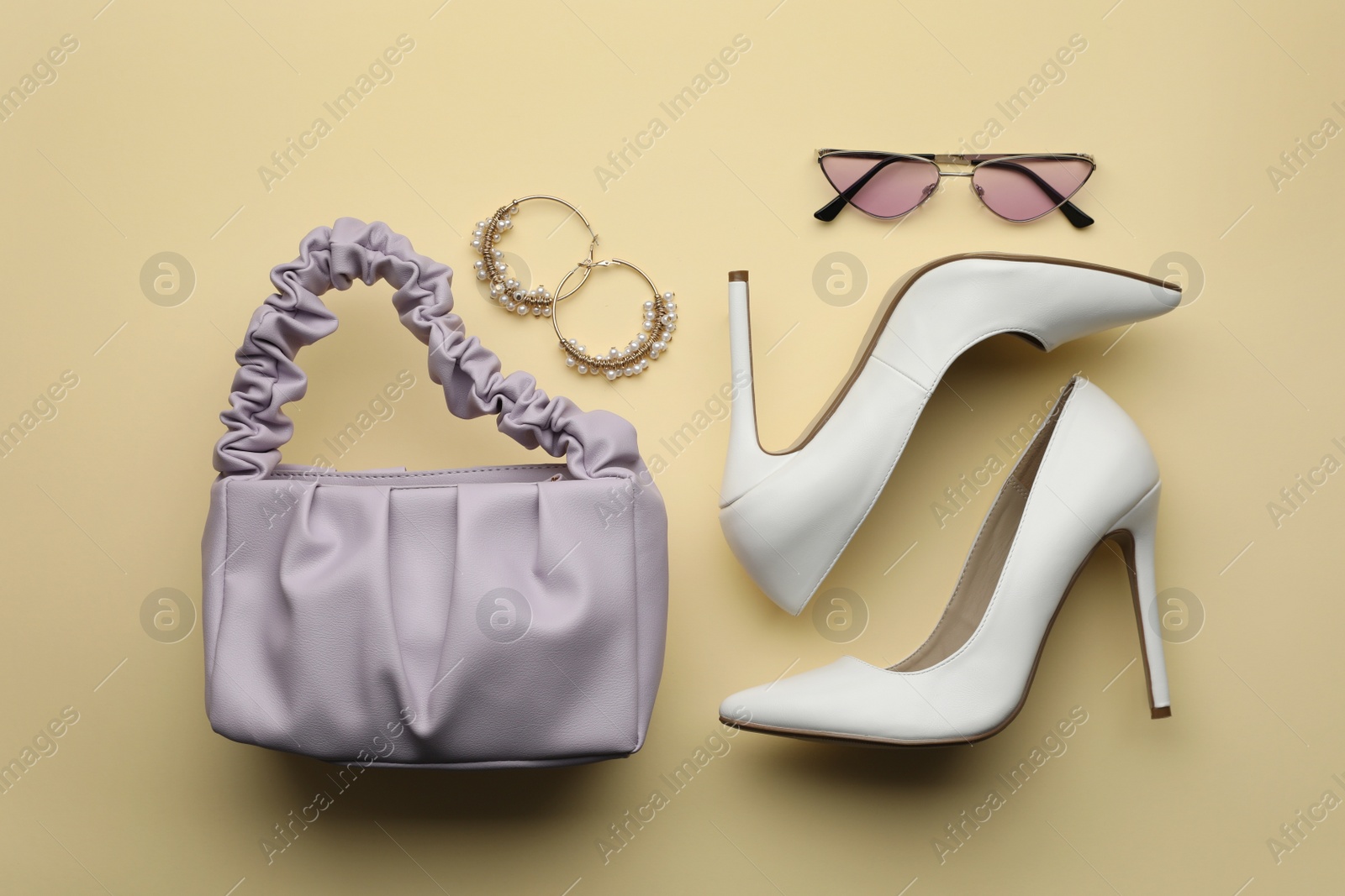 Photo of Stylish woman's bag, shoes, earrings and sunglasses on beige background, flat lay