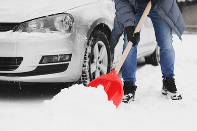 Photo of Man removing snow with shovel near car outdoors, closeup