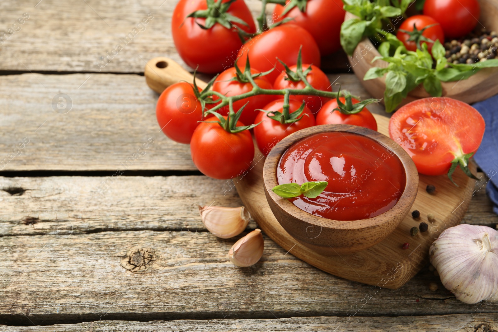 Photo of Tasty ketchup, fresh tomatoes, basil and spices on wooden table. Space for text