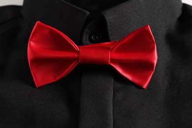 Photo of Black shirt with stylish red bow tie, closeup