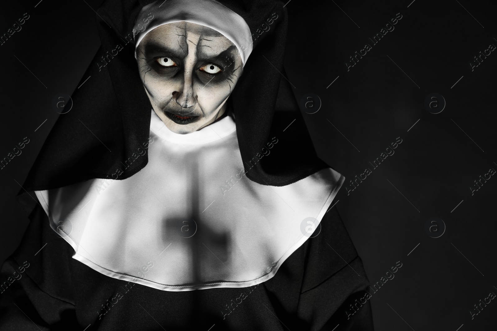 Photo of Portrait of scary devilish nun on black background, space for text. Halloween party look